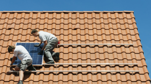 Workers installing solar panel on roof framework of new home, Netherlands