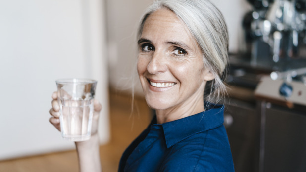 Portrait of smiling businesswoman holding glass of water