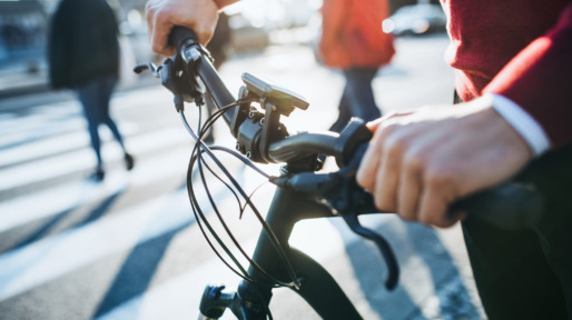A midsection of businessman commuter with electric bicycle traveling to work in city.