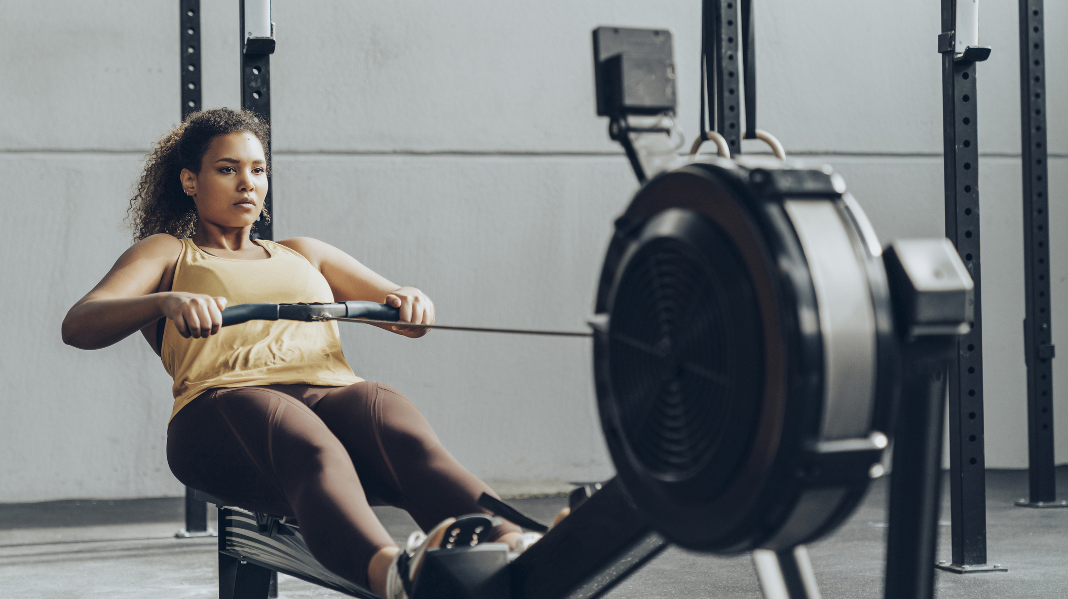 Young woman exercising in gym with rowing machine