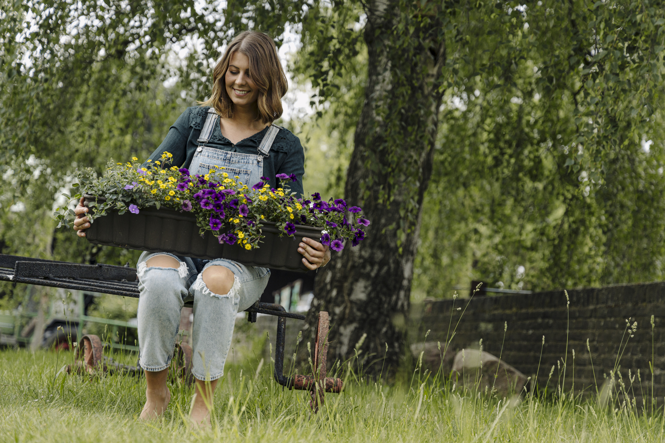 Smiling young woman with flower box on a meadow