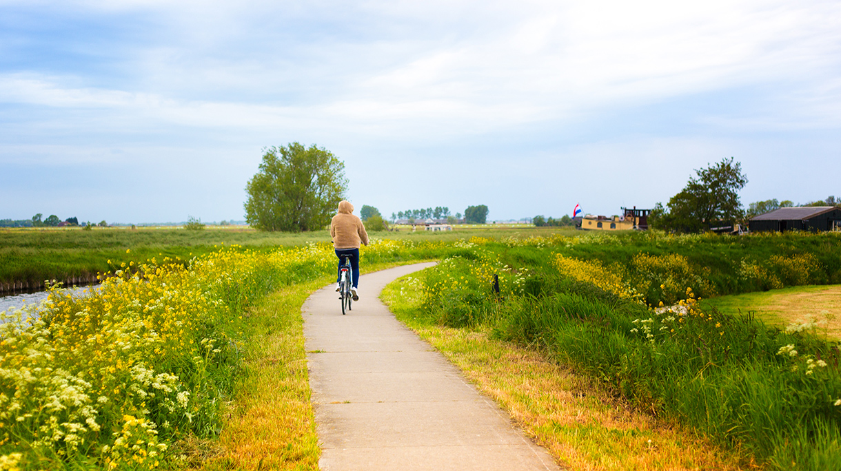 Young Woman Cyclist near Canal, Springtime (Netherlands)