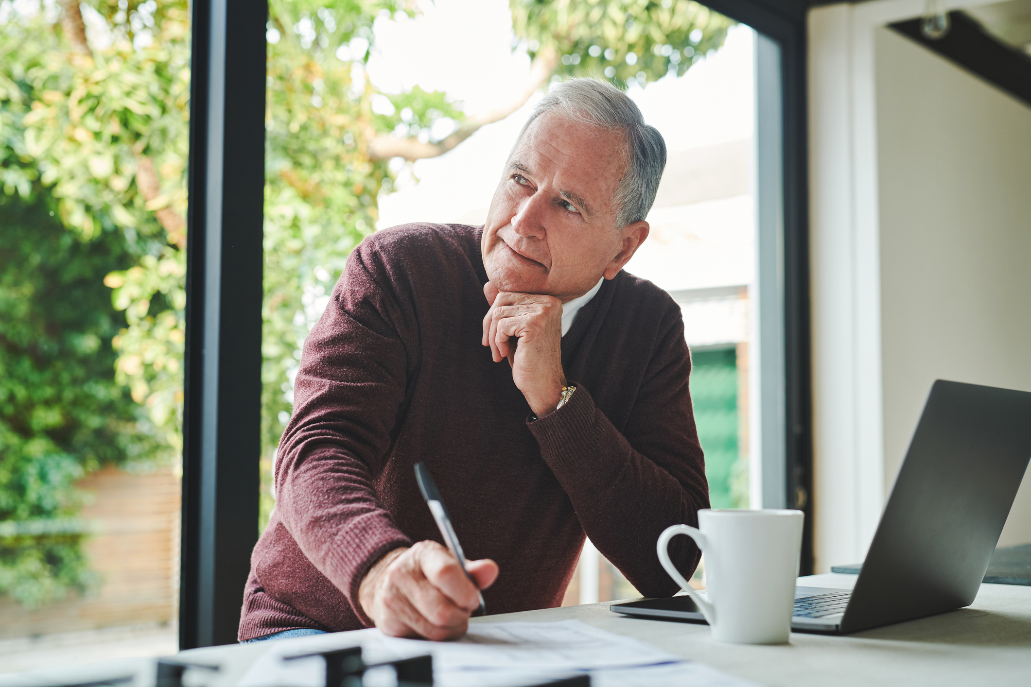 Shot of a senior man sitting alone at home and looking contemplative while calculating his finances