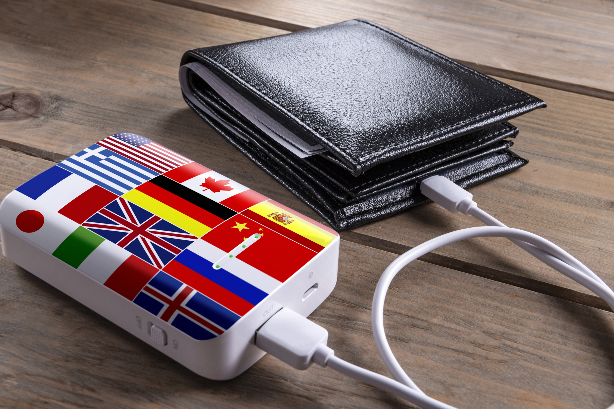 Money wallet and flag patterned power bank on wood desk.