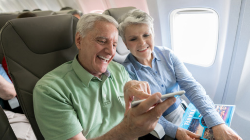 Senior couple traveling by plane and using their cell phone onboard