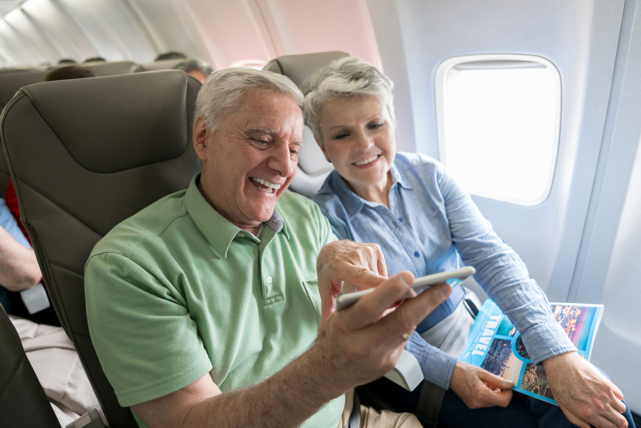 Senior couple traveling by plane and using their cell phone onboard