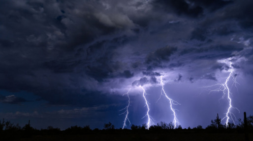 Low Angle View Of Lightning Over Silhouette Landscape At Night