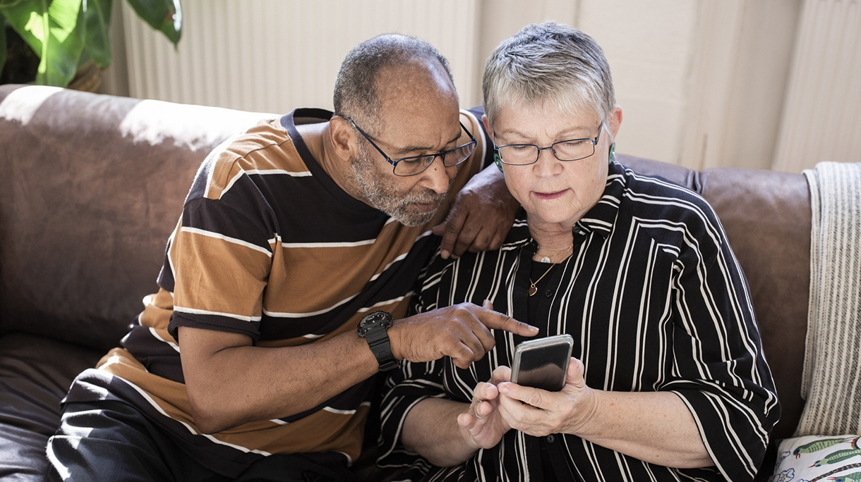 Senior couple using smart phone in living room