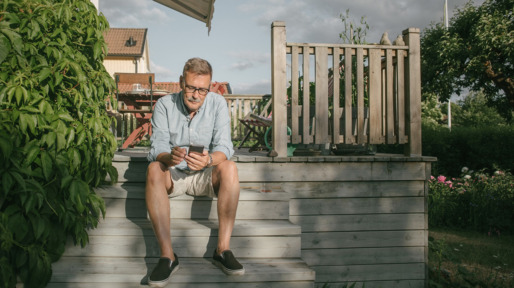 Full length of senior man using mobile phone while sitting on steps at porch