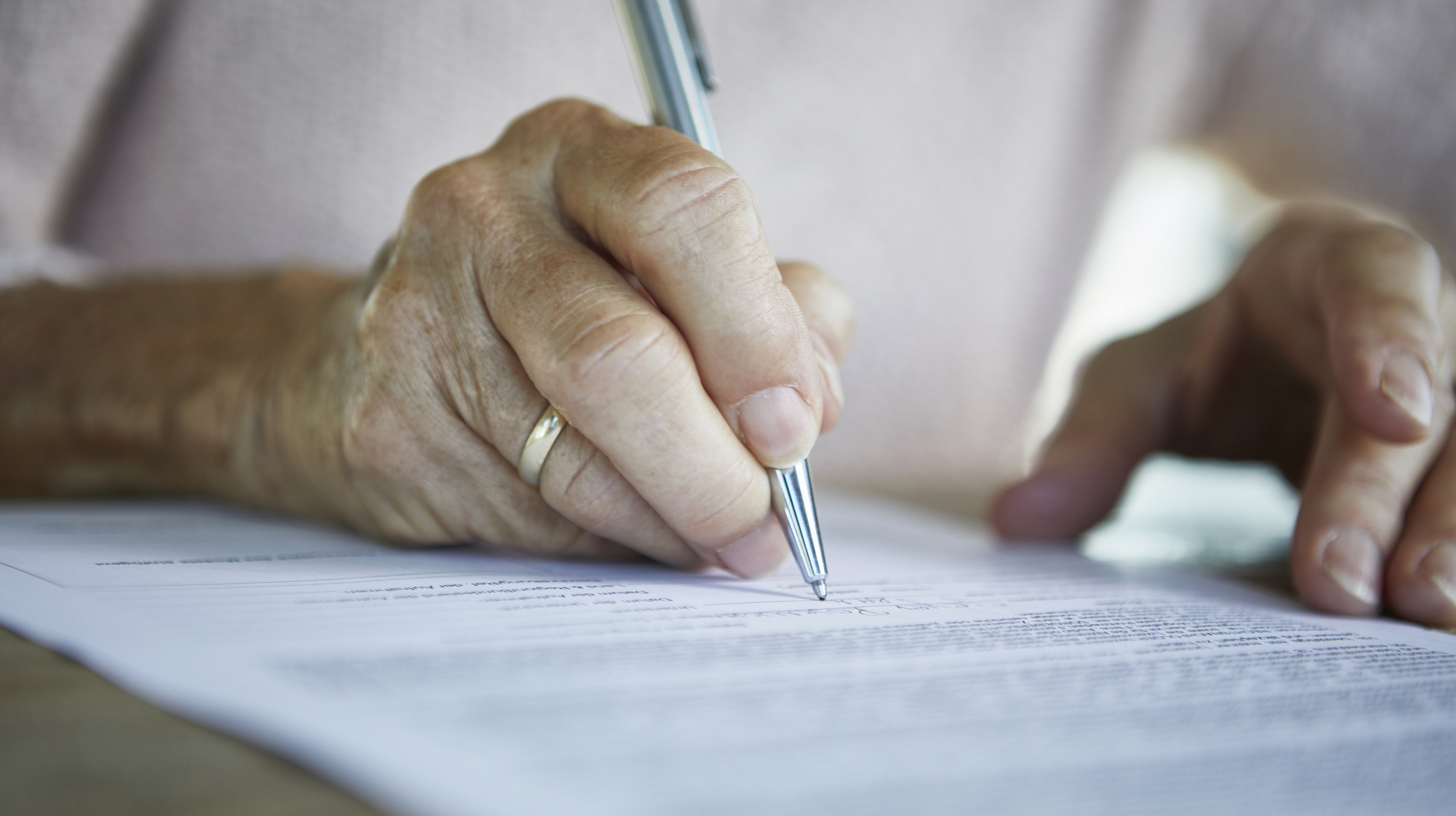 Senior woman’s hand signing a document, close-up