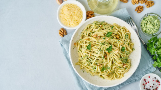 Pesto pasta, bavette with walnuts, parsley, garlic, nuts, olive oil. Top view, copy space, blue background.