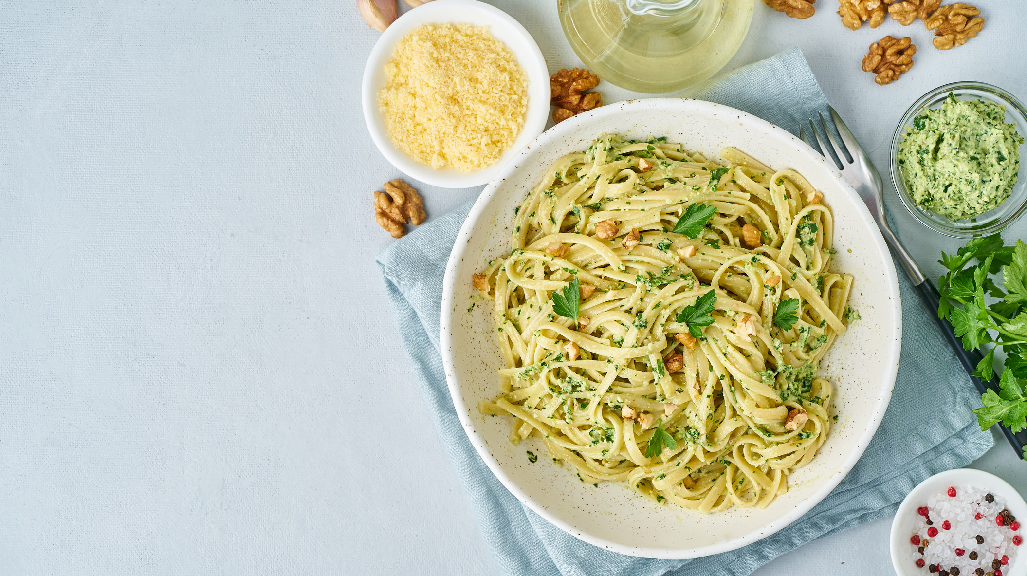 Pesto pasta, bavette with walnuts, parsley, garlic, nuts, olive oil. Top view, copy space, blue background.