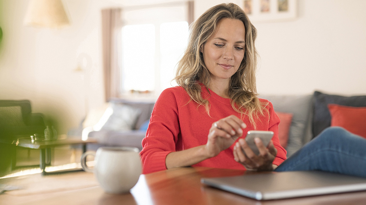 Woman using cell phone on dining table at home