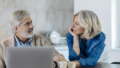 Mature man with wife using laptop on kitchen table at home
