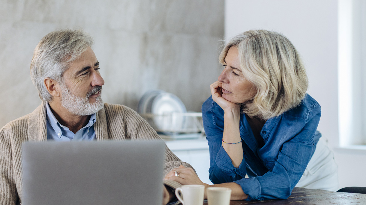 Mature man with wife using laptop on kitchen table at home