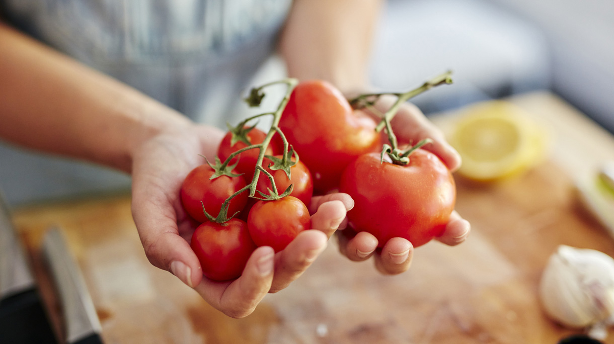 Woman holding different sized organic tomatoes in kitchen