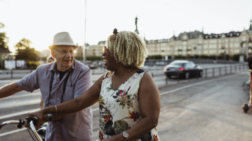 Cheerful couple with bicycle on road in city