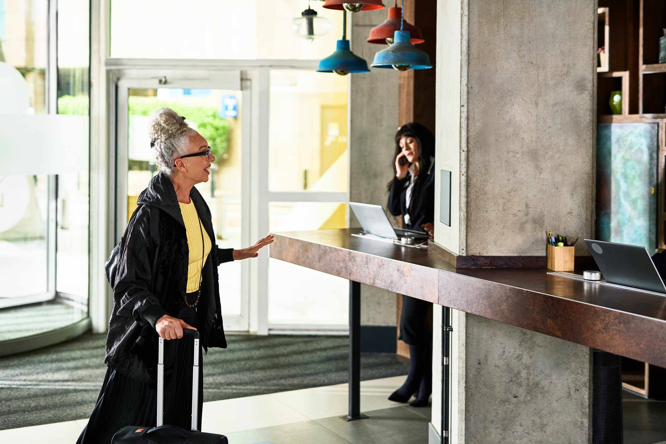 Senior woman with luggage arriving in hotel lobby