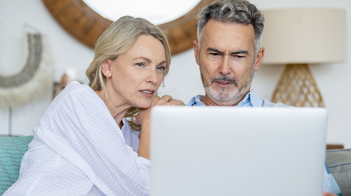 Mature couple using laptop computer sitting on the sofa.