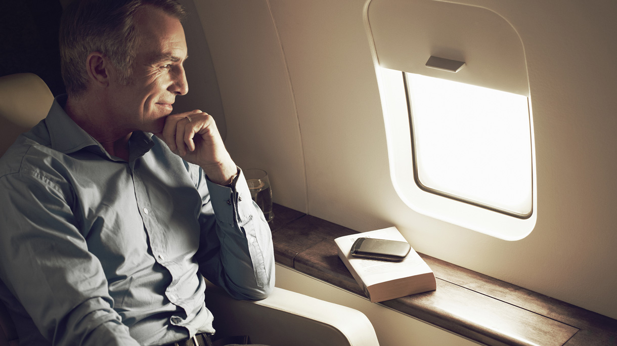 Businessman gazing out of window aboard flight