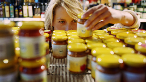 Young woman selecting jar from shelf in shop (focus on woman’s face)