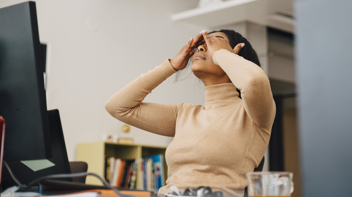 Frustrated female computer programmer with head in hands sitting in creative office