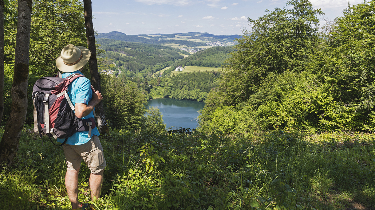 Senior hiker admiring landscape surrounding Gemundener Maar lake
