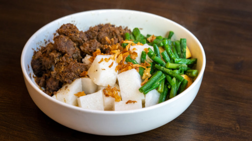 A plate of Javanese food with beef rendang , lontong rice and green beans