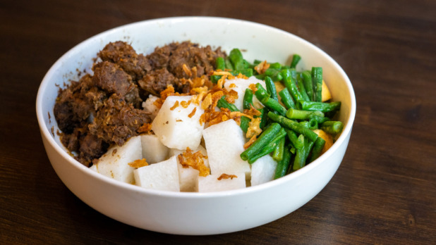 A plate of Javanese food with beef rendang , lontong rice and green beans