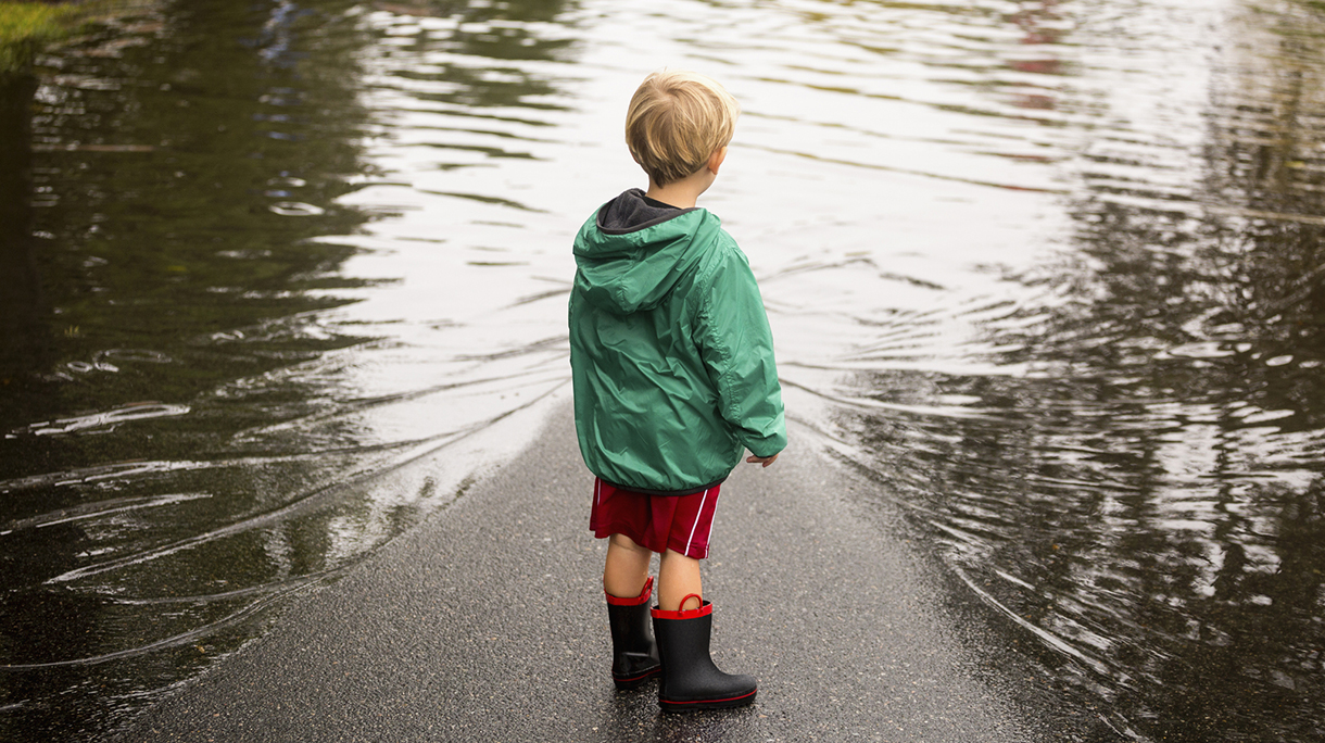 Caucasian boy wearing puddles near flood