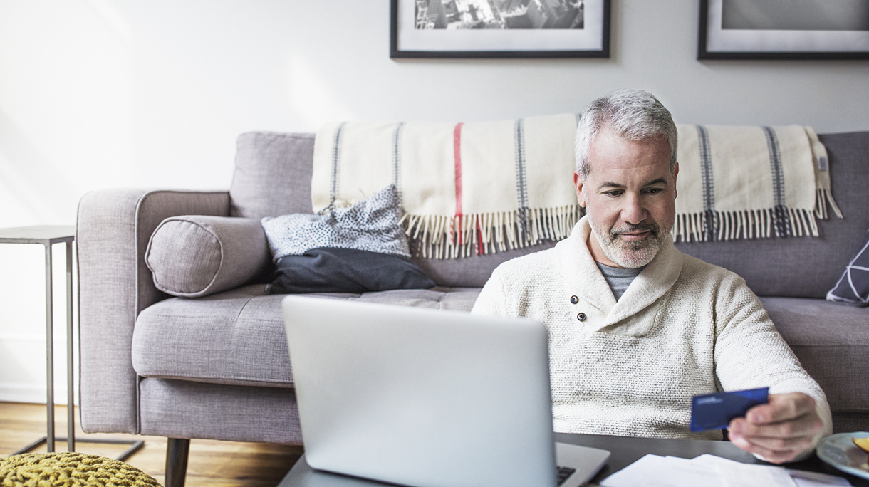 Mature man using credit card and laptop while shopping online at home