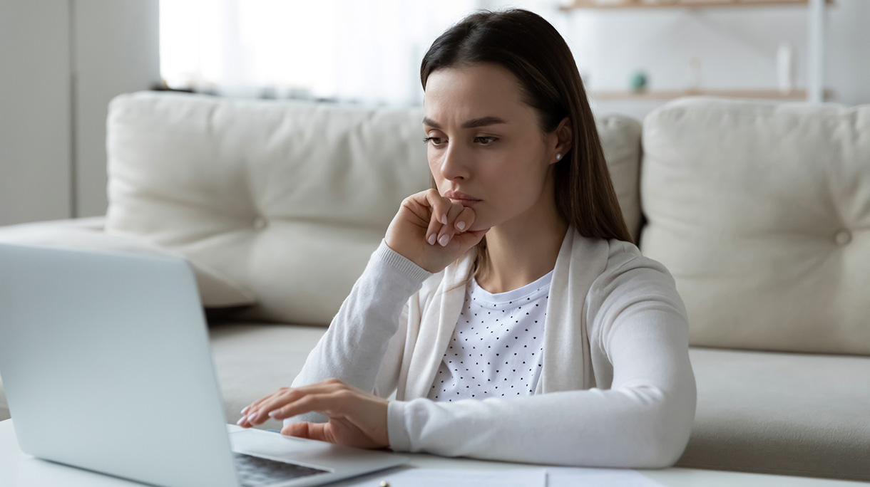 Confused unhappy young woman looking at computer screen.