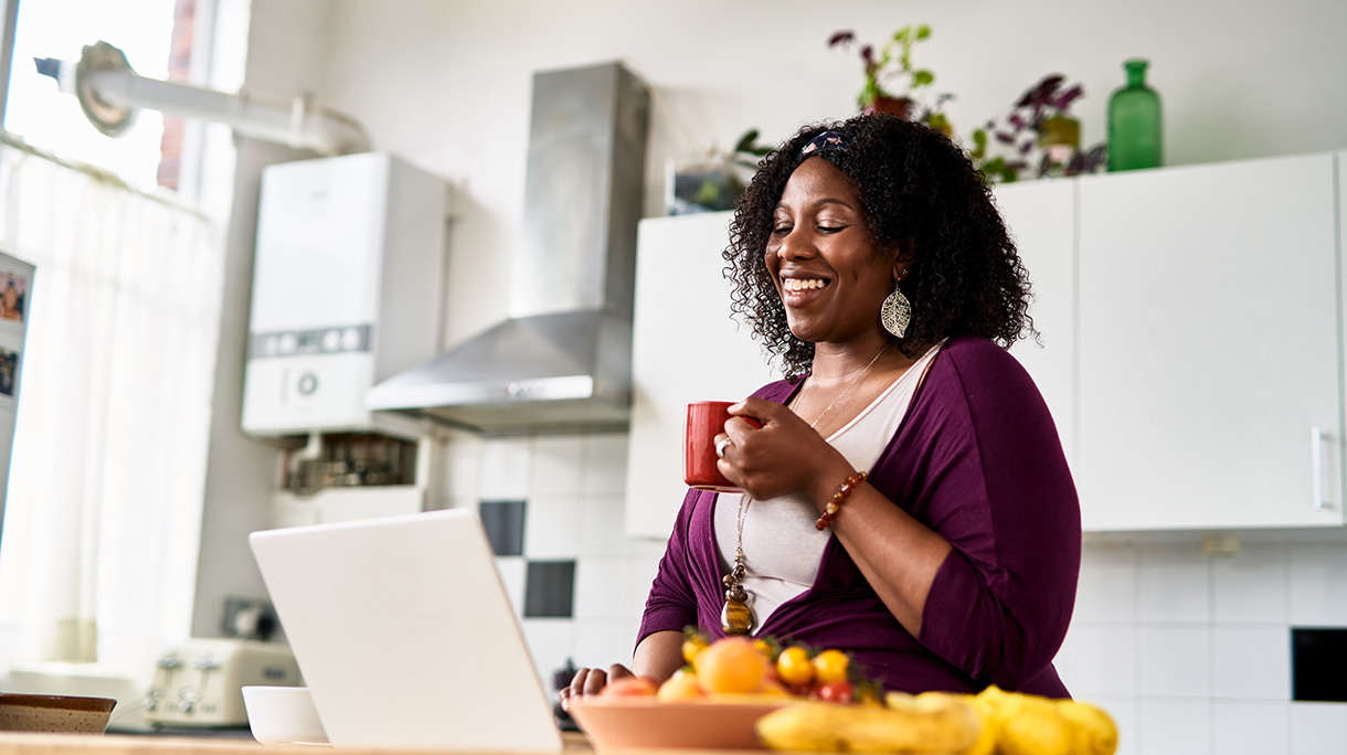 Cheerful mid adult woman using laptop and smiling in online meeting