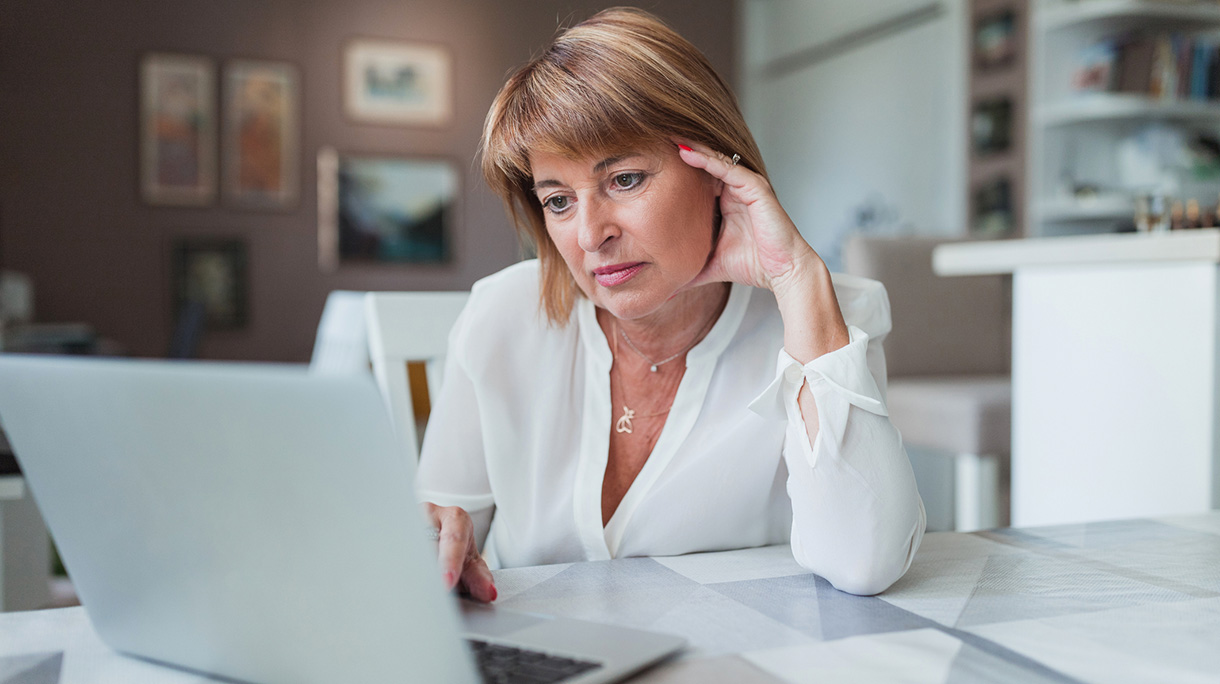 Displeased mature business woman using laptop