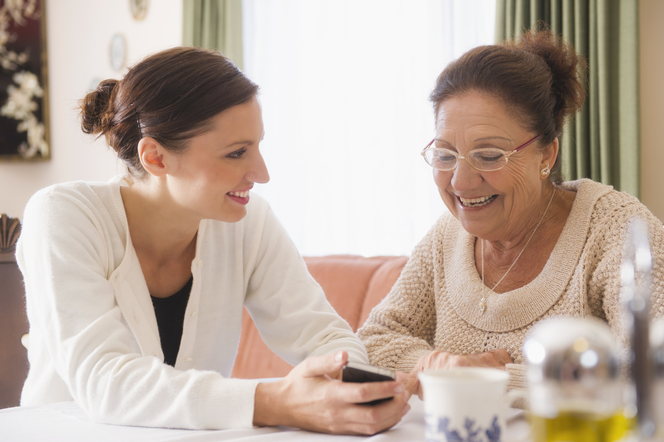 Hispanic woman showing cell phone to grandmother