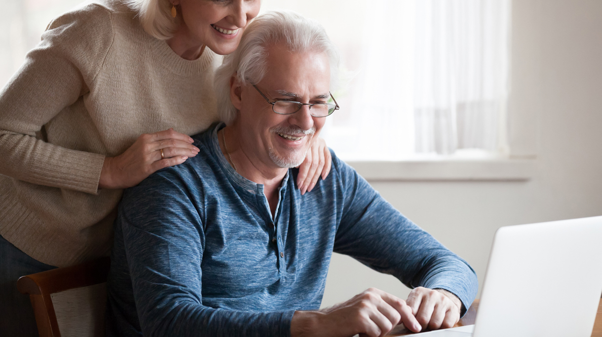 Happy aged couple looking at laptop screen smiling