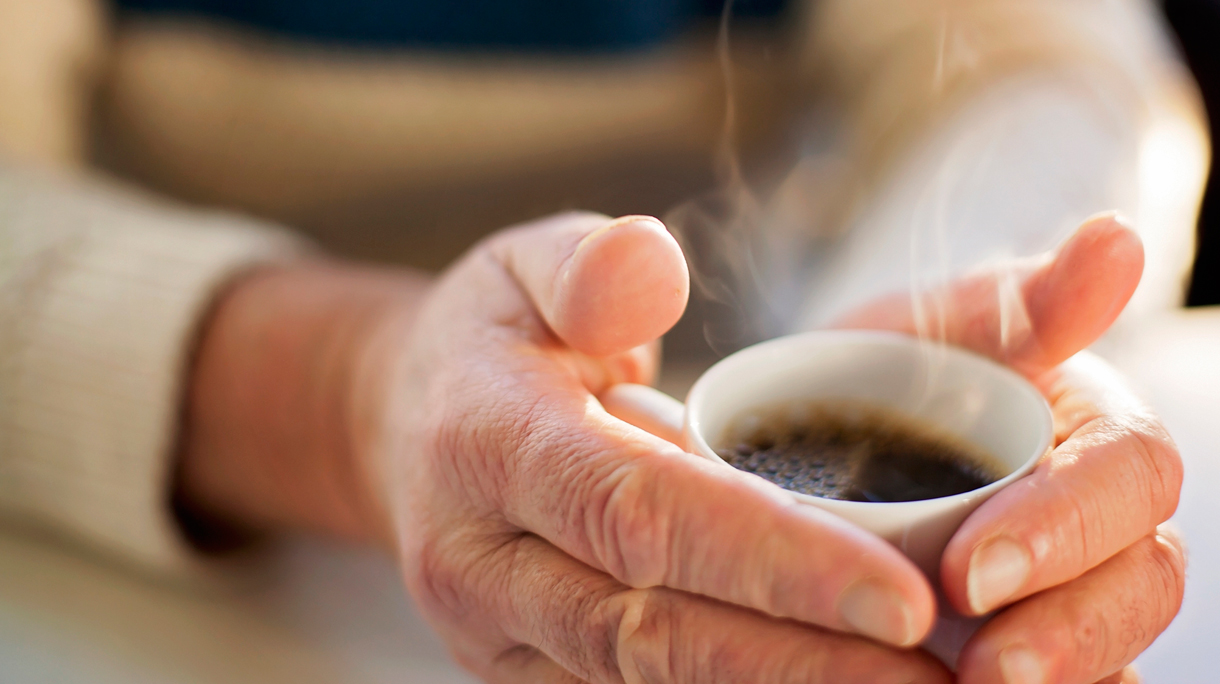 Vrouw warmt handen aan koffie