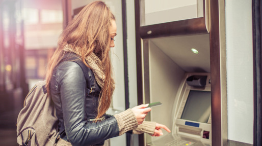 Young woman taking money from ATM