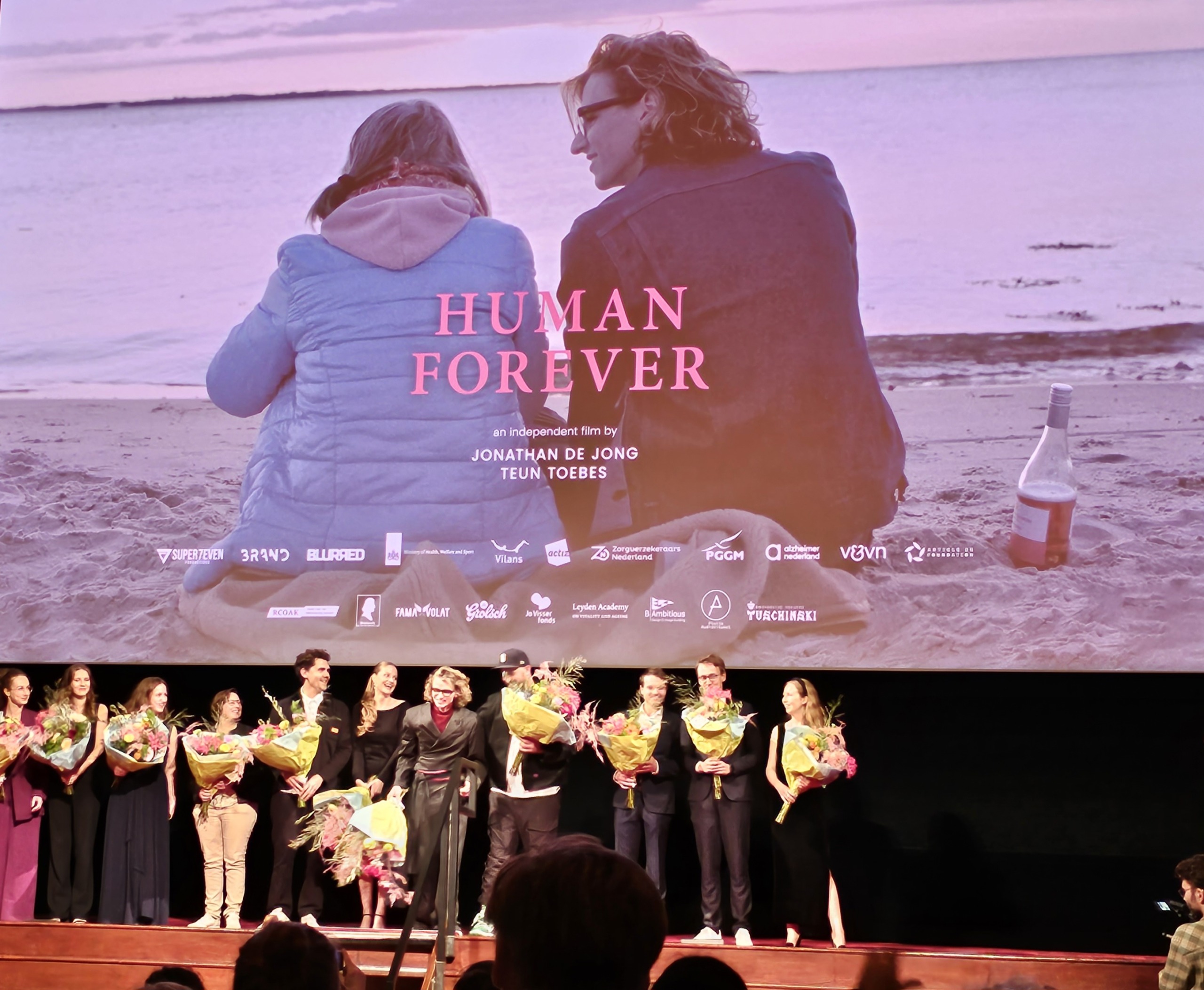 De filmposter van Human Forever en de crew op de premiere op 9 oktober in Amsterdam