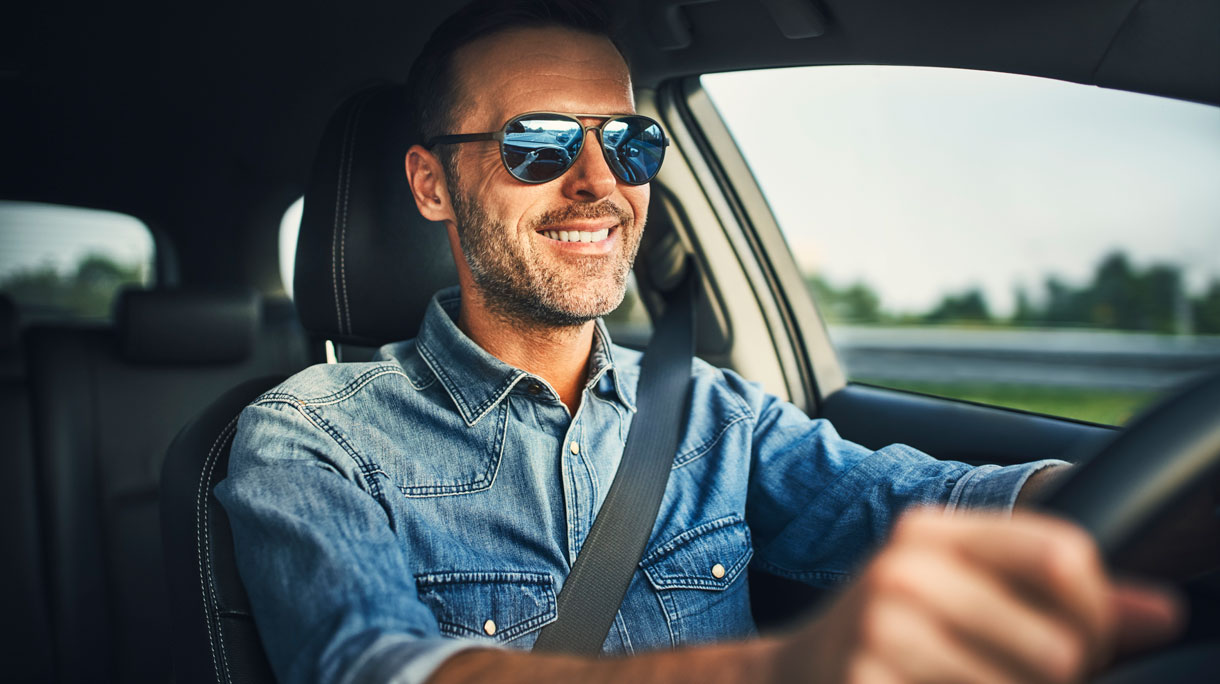 Man met zonnebril op achter het stuur van een auto