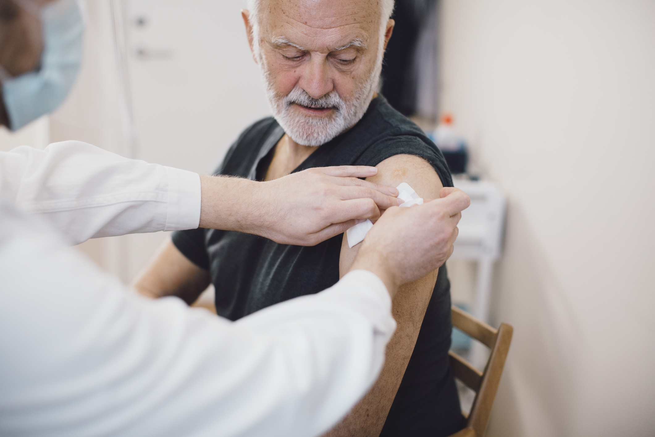 Vaccinatie oudere man krijgt prik van vrouwelijke arts