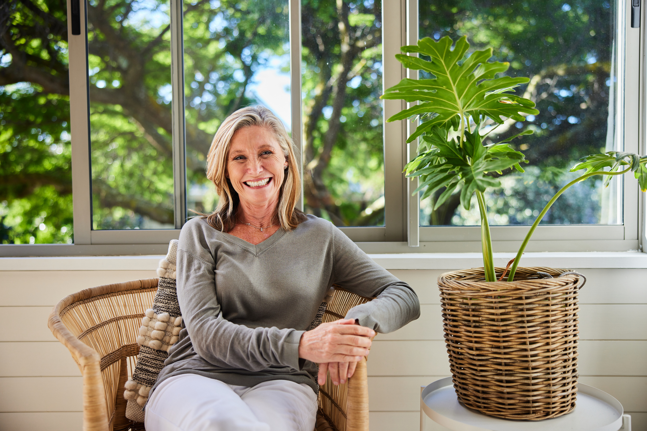 Blanke vrouw op stoel in de woonkamer met groene tuin