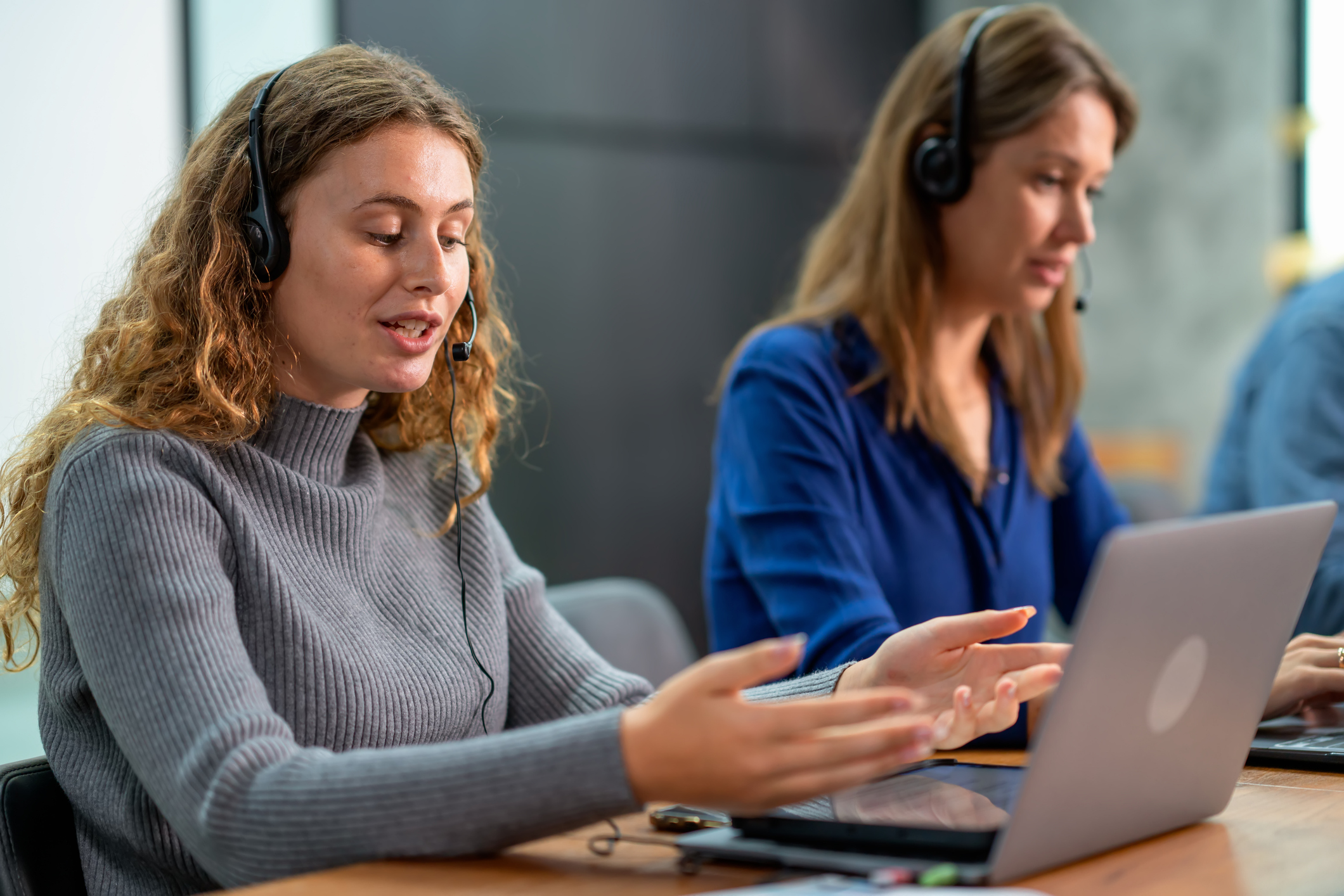 Bank helpdesk vrouw legt uit aan klant met laptop, vrouwelijke collega naast haar