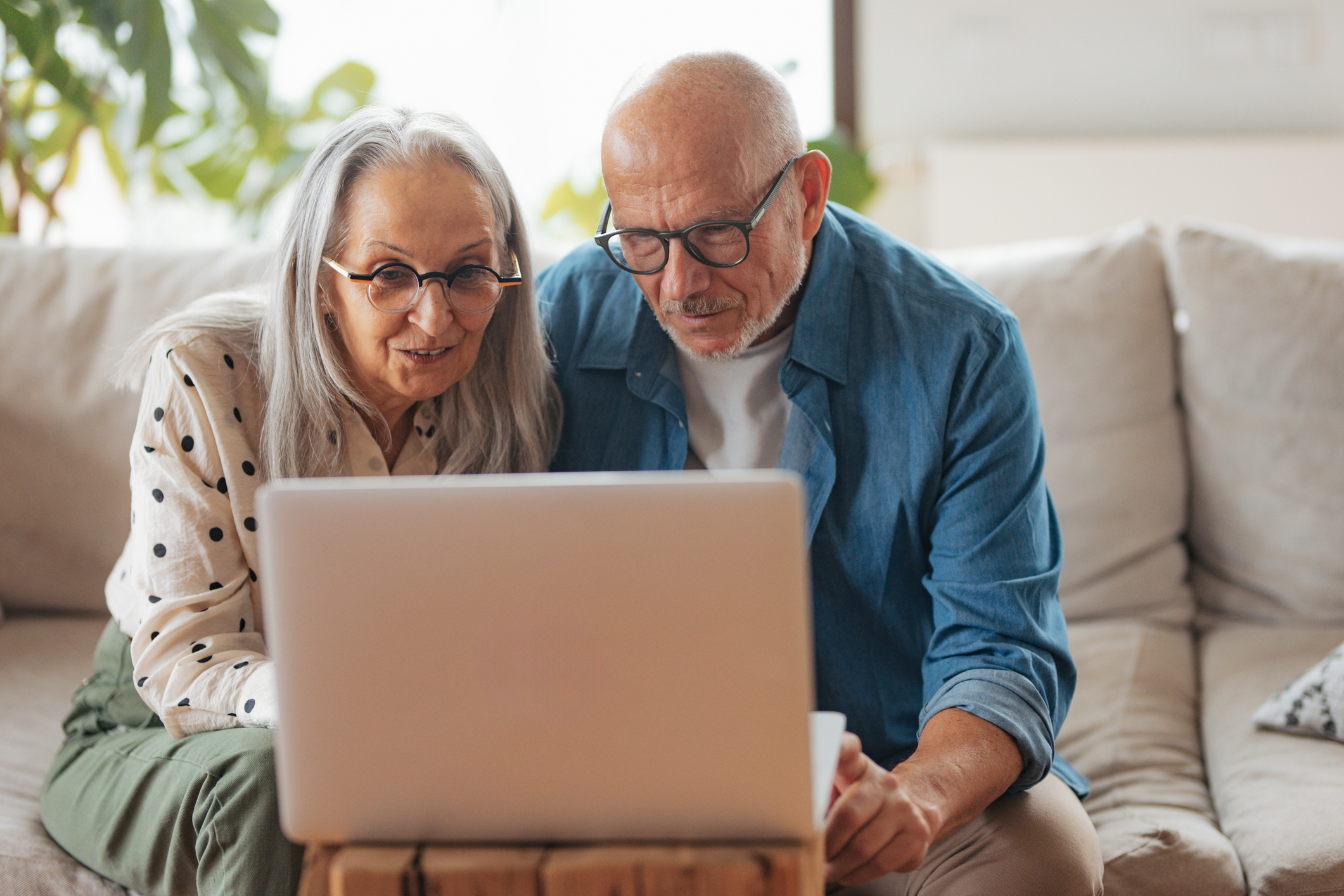 Man en vrouw bestuderen laptop op de bank in de woonkamer