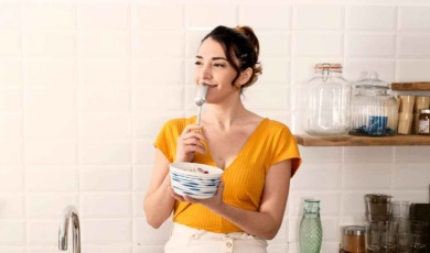 Vrouw zit op aanrecht yoghurt te eten
