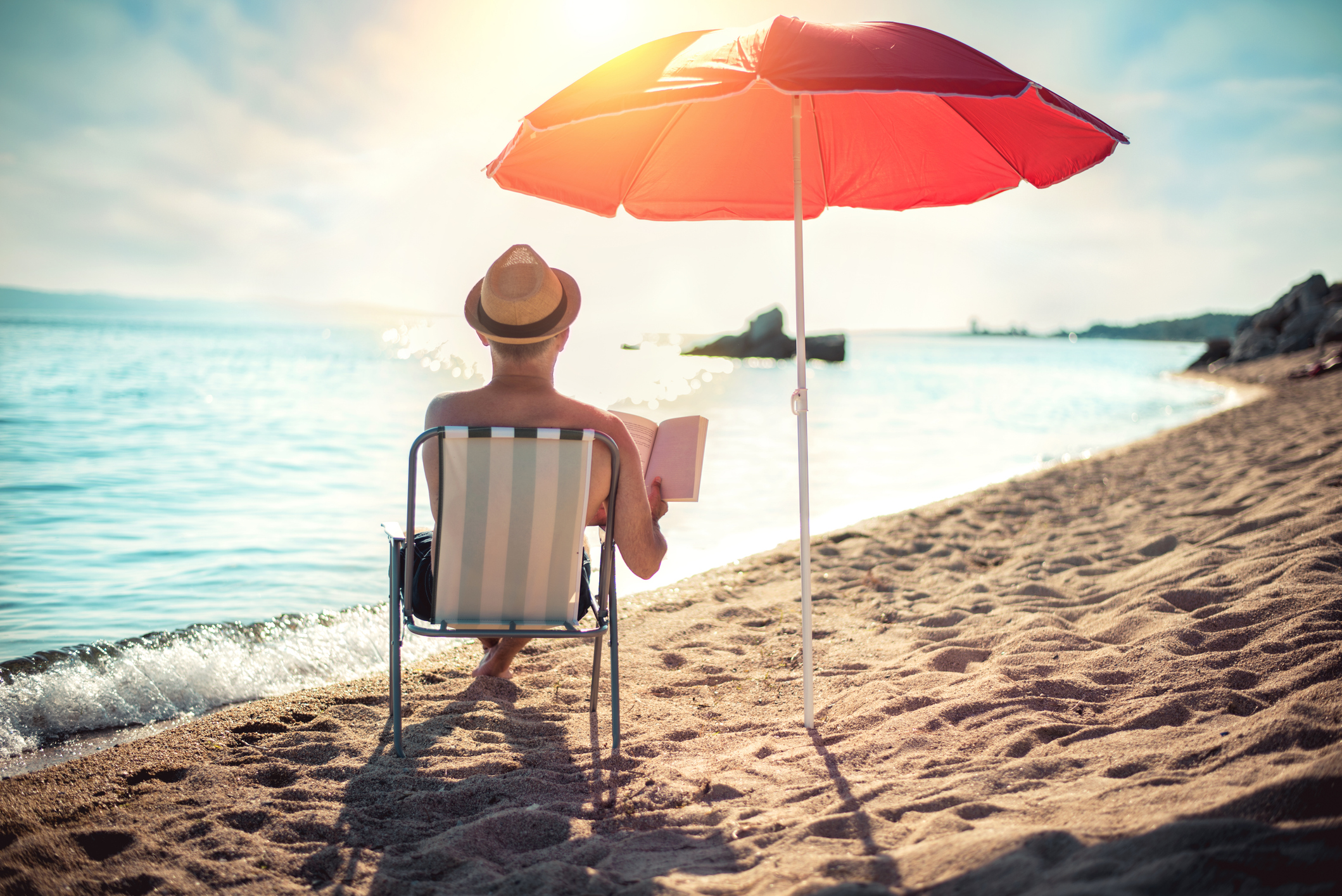 Man zit onder zijn parasol te lezen