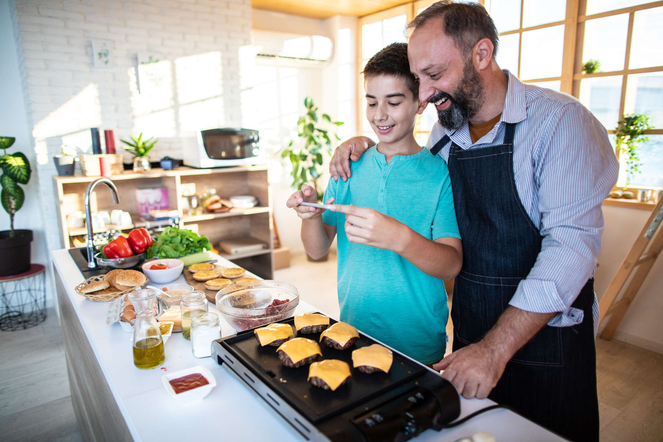 Hamburgers bakken vader en zoon in de keuken met kaas