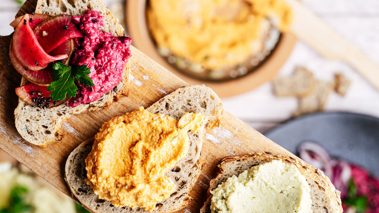 Verschillende soorten hummus op een plakje stokbrood