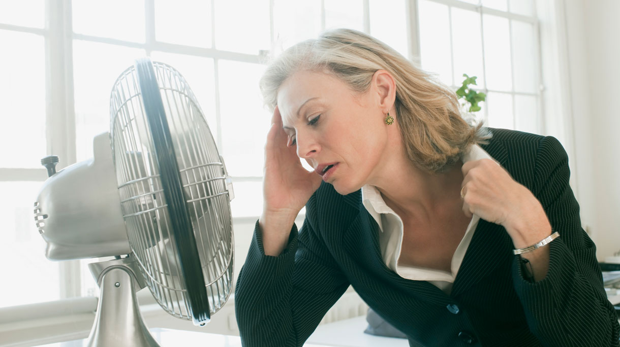 Vrouw heeft het warm en zit voor ventilater om af te koelen