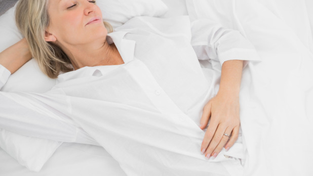 Vrouw ligt in bed op hoofdkussen